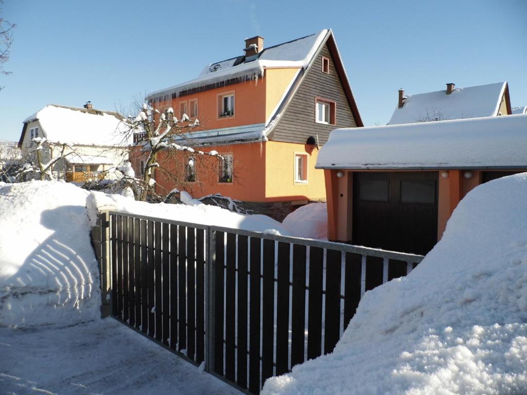 a fence covered in snow next to a house at Apartment Na Pražské Vrchlabí in Vrchlabí