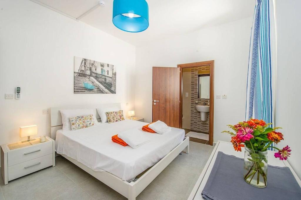 a bedroom with a white bed and a vase of flowers at Hillock Residence Marsalforn in Marsalforn