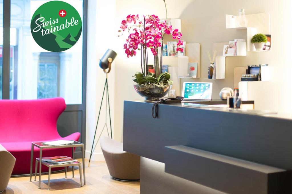an office with a desk with a laptop and a pink chair at Hôtel des Voyageurs Boutique in Lausanne