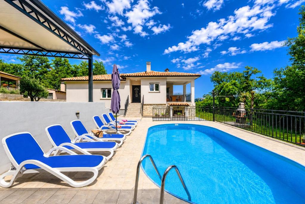 a pool with lounge chairs next to a house at House Luka by Briskva in Krapan