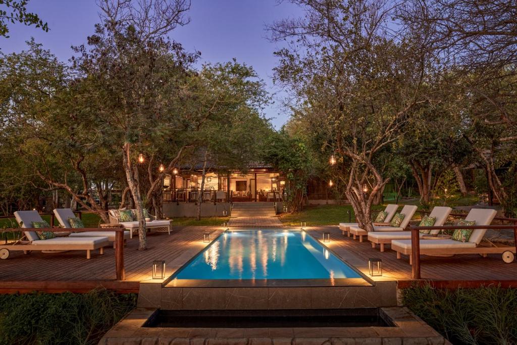 a swimming pool with lounge chairs and a house at Taj Bush Lodge in Hoedspruit