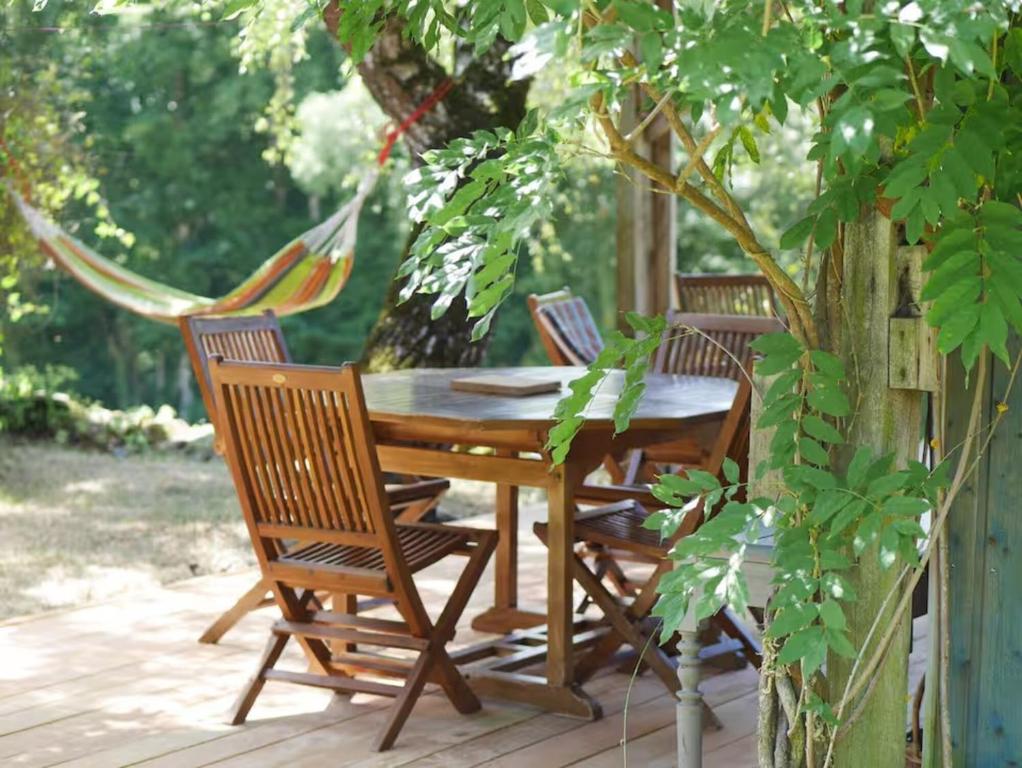 a wooden table and chairs on a deck with a hammock at Maison La Voyageuse in Gorses