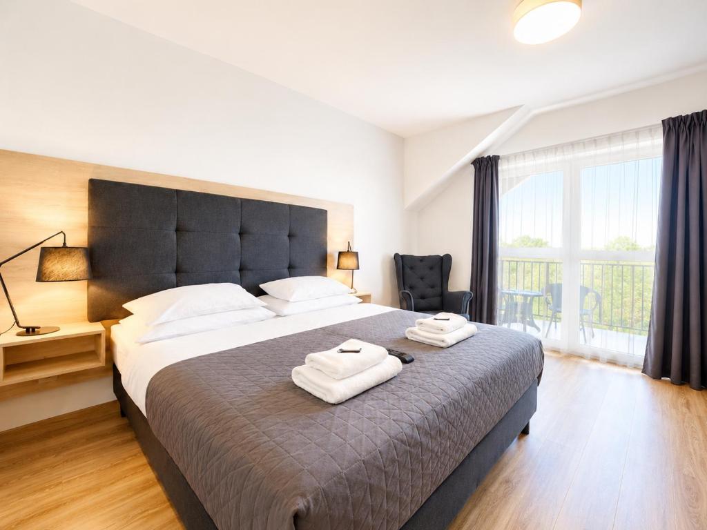 a bedroom with a large bed with two towels on it at ROYAL Villa RESORT & SPA - Jacuzzi, Sauna, MELEX na plażę, Masaże, Apartamenty z kuchnią, Widok na Zalew Wiślany in Krynica Morska
