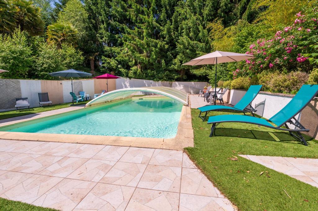 a swimming pool with two chairs and an umbrella at Domaine des légendes in Plumelin
