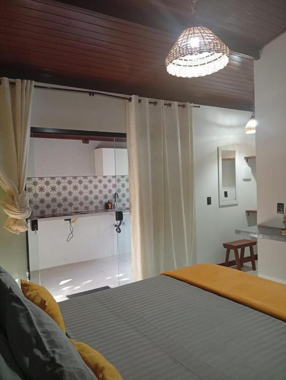a bedroom with a bed and a chandelier at Jardim dos Milagres Suítes in São Miguel dos Milagres
