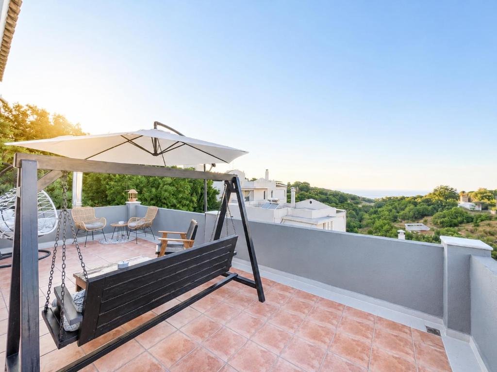 eine Terrasse mit Bank und Sonnenschirm in der Unterkunft An Drea Between in Gerani