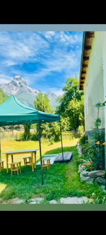 a green umbrella and a picnic table and a bench at Dali Kaldanis Guest House in Becho in Mestia