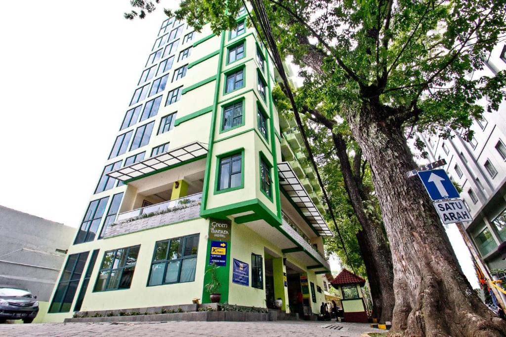 un edificio verde y blanco con un árbol delante en Green Batara Hotel, en Bandung