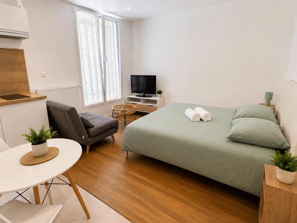 a bedroom with a bed and a chair and a television at Centre ville - Houilles A1 in Houilles