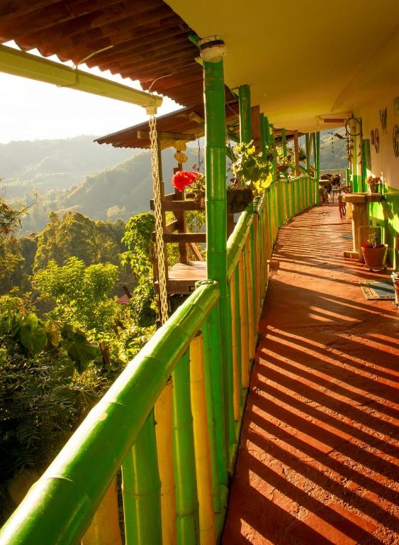 a green balcony with a view of the mountains at Hostal y Camping Los Girasoles in Salento