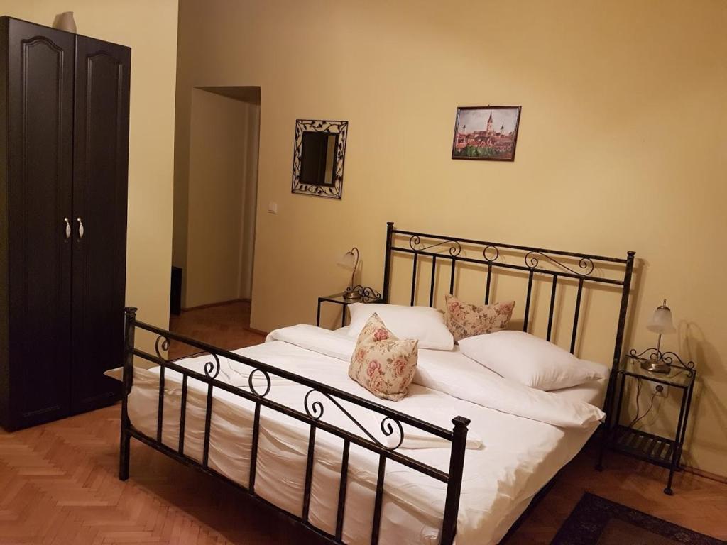 una camera da letto con letto, lenzuola e cuscini bianchi di Central Square Studios a Sibiu