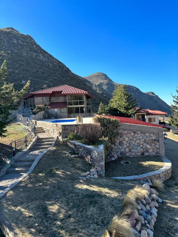 a building with a stone wall next to a mountain at Hotel de la Cañada Valle de Uco in Tunuyán