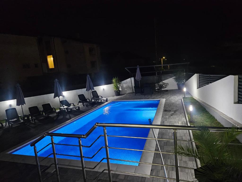 a swimming pool at night with chairs and umbrellas at Studio nikola in Soko Banja
