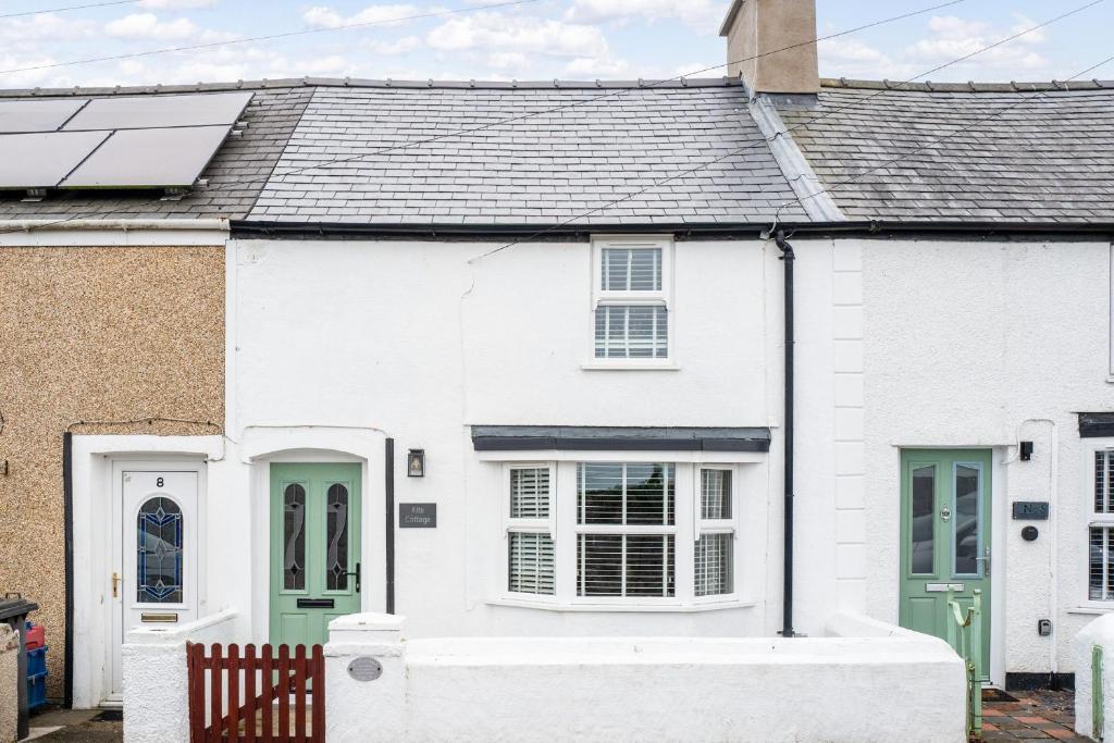 a white house with green doors at Kite Cottage in Llangadwaladr
