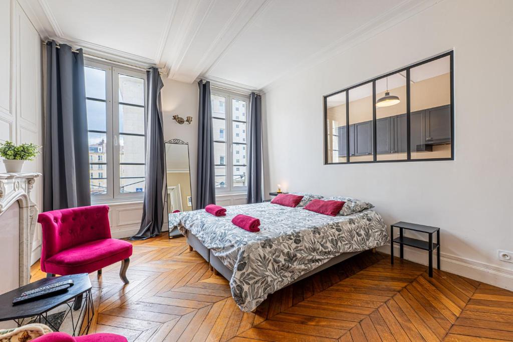 a bedroom with a bed and a pink chair at Federer - Dans l'hypercentre de Caen in Caen