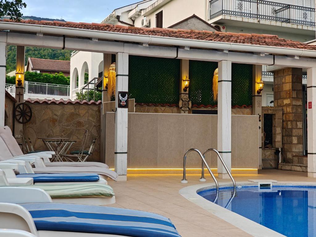 a pool with lounge chairs next to a building at Mila & Aleksandr Apartments in Budva