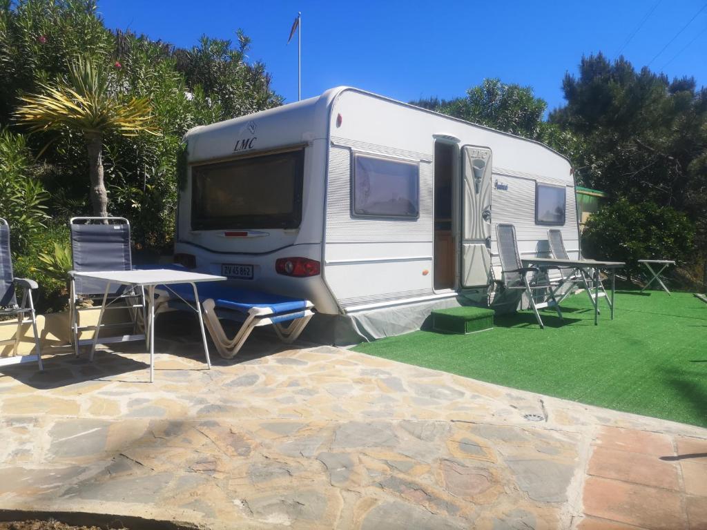 a white rv parked with a table and chairs at Roca Caravan in Estepona