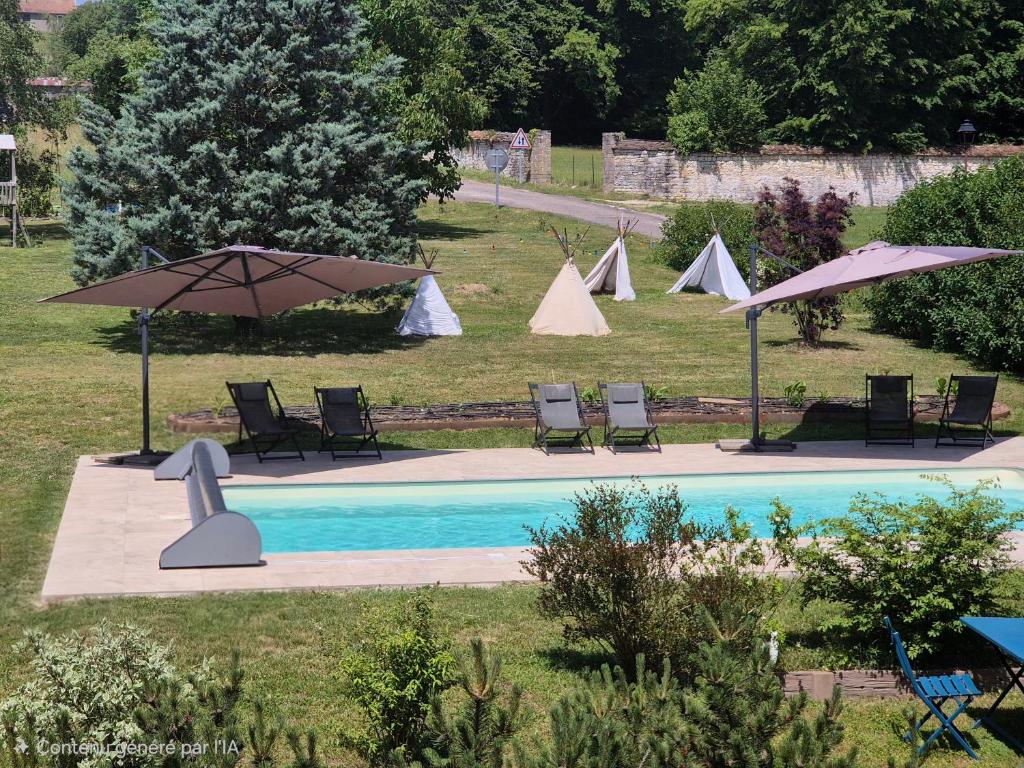 a swimming pool with chairs and umbrellas next to a field at Le Tilleul de Ray in Ray-sur-Saône