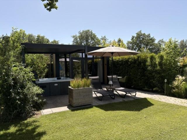 a gazebo with a picnic table and an umbrella at Wellnesslodge Specht jacuzzi and sauna and privacy in Dalerveen
