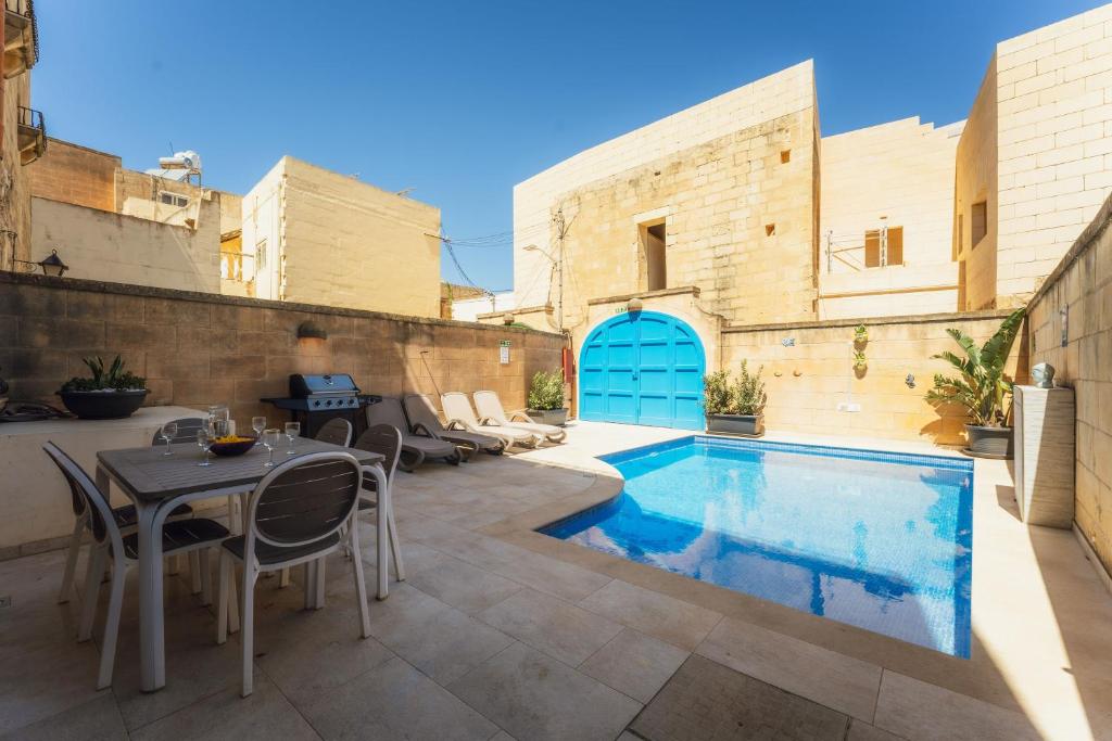 a patio with a pool and a table and chairs at Authentic Xagħra Farmhouse with Private Pool in Xagħra