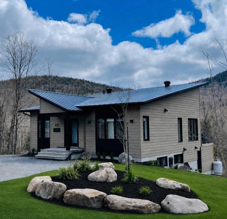a house with rocks in front of it at Ski in - Ski out - SPA & Pool Table - Le Konect in Saint-Philémon