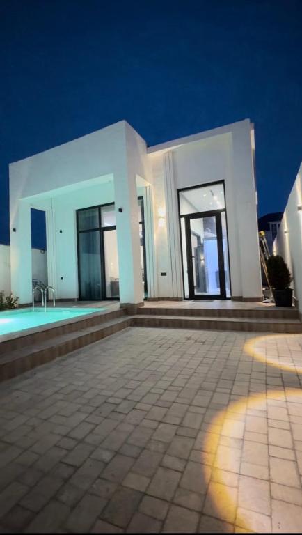 a white house with a swimming pool at night at Palm Villa in Mərdəkan