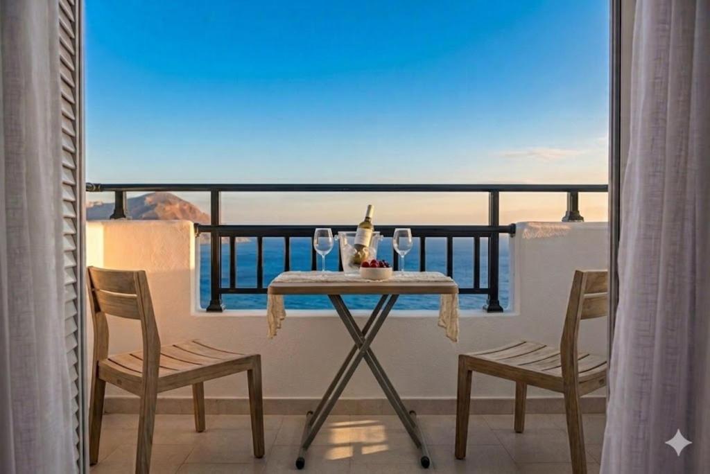 a table with two chairs and wine glasses on a balcony at Antigoni in Agia Galini