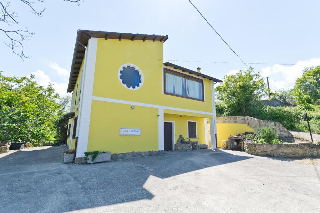 a yellow house with a clock on the side of it at Casale Rustico ColleBello in Castiglione Messer Raimondo