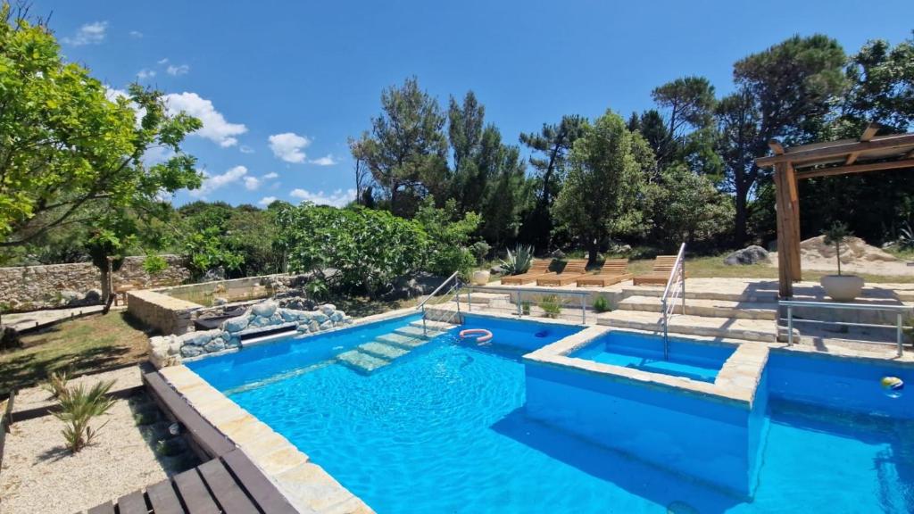 a swimming pool with blue water in a yard at 4Rest Villa in Novalja