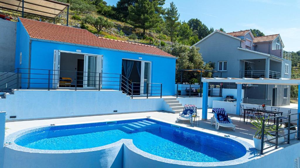 a blue house with a swimming pool next to a house at Villa Love house in Vela Luka