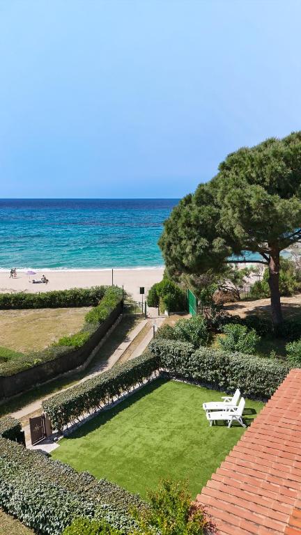 a white bench sitting on the grass near the beach at Villa Giulia seafront in Marongiu