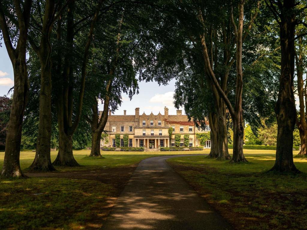 Ein Weg vor einem großen Haus mit Bäumen in der Unterkunft Lucknam Park, Emblems Collection in Chippenham
