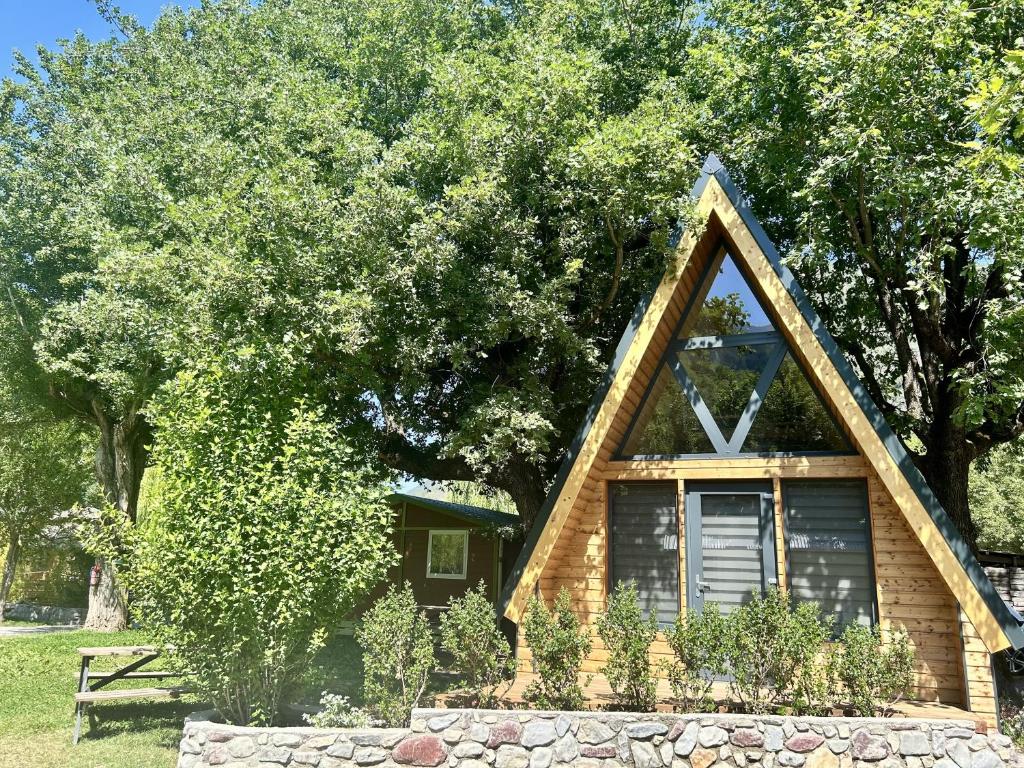 a house with a triangular roof and a stone wall at Tiny house au coeur de la nature in Touët-sur-Var