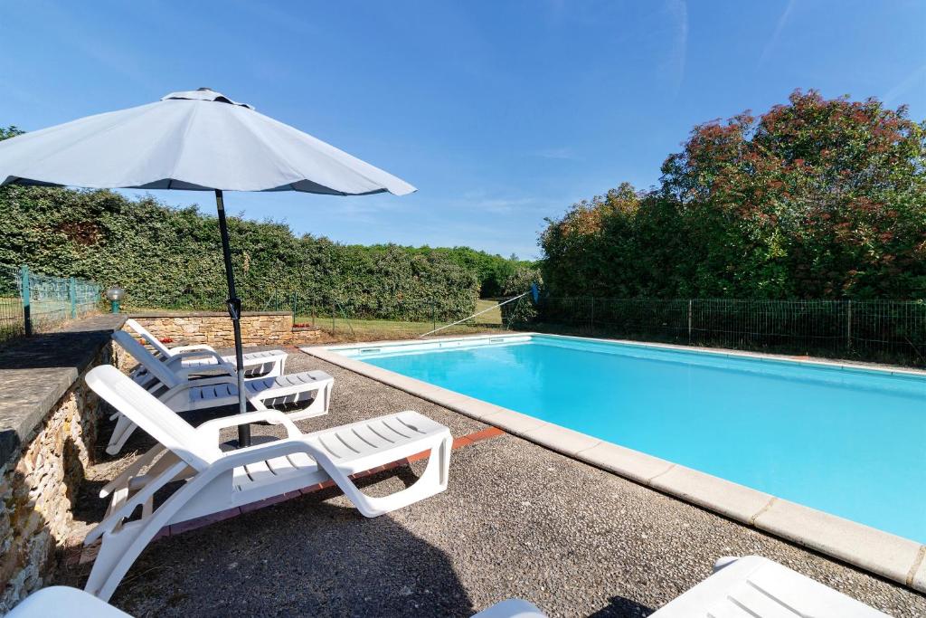 a pair of chairs and an umbrella next to a swimming pool at Maison de vacances Le Tilleul in Saint-Pompont