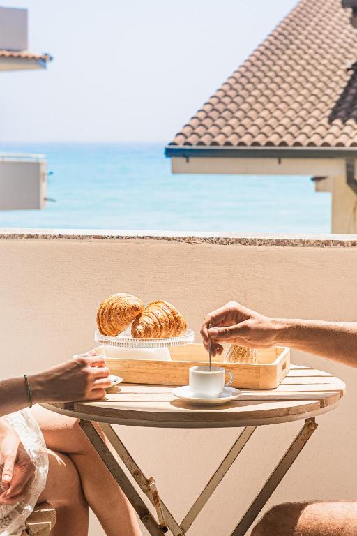 two people sitting at a table with a tray of pastries at B&B a due passi dal mare in Caulonia Marina