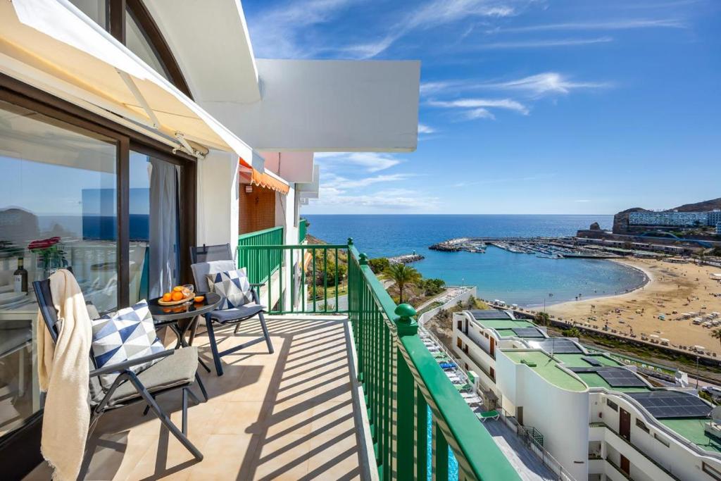 a balcony with chairs and a view of the beach at Modern Sea View Apartment Near Beach & Pool Puerto Rico in Puerto Rico de Gran Canaria