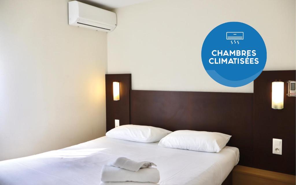 a bed with white sheets and a sign on the wall at Brit Hotel Essentiel Reims Taissy in Reims
