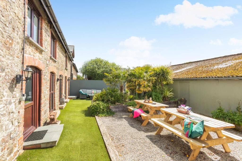 a patio with wooden tables and benches in a yard at 6 Bed in Holsworthy oc-89218 in Merryfield