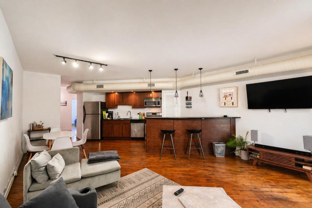 a living room with a couch and a tv and a kitchen at The Havana Lofts in Philadelphia