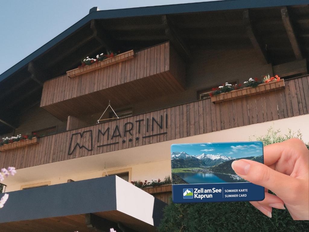 a person holding up a card in front of a building at Hotel Martini Kaprun including free parking and Zell am See-Kaprun summer card in Kaprun