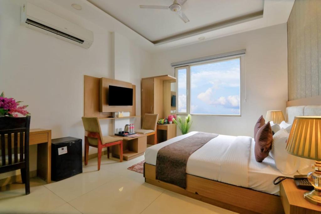 a bedroom with a bed and a desk and a window at Hotel Olive Aero Suites By Signature Stayz Near Delhi Airport in New Delhi