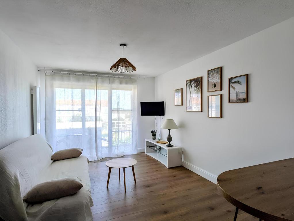 a white living room with a couch and a table at Le cocon de Marennes in Marennes