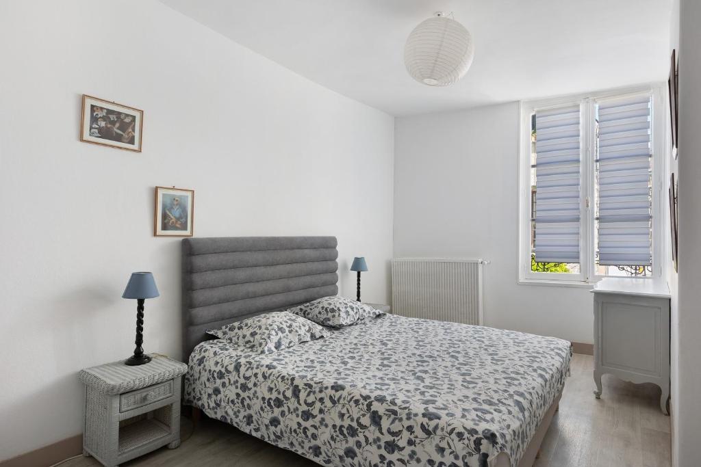 a white bedroom with a bed and a window at Coeur de Ville - Beaugency in Beaugency