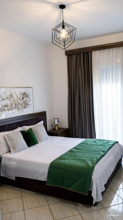 a bedroom with a large bed with a green blanket at Villa Doka in Sarandë