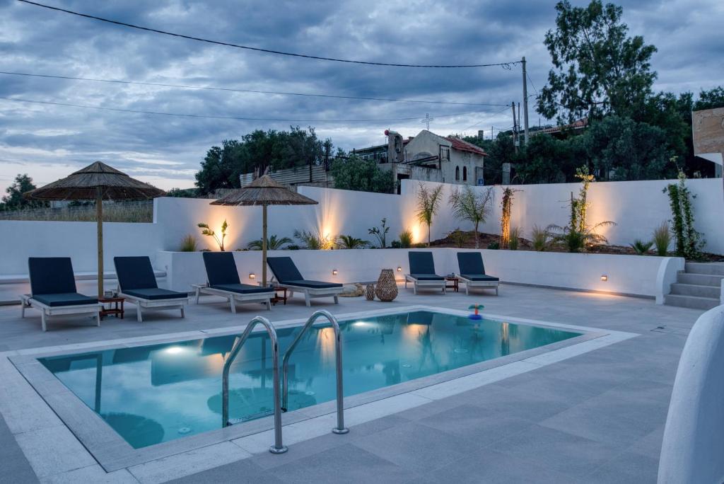 a swimming pool in a backyard with chairs and a fence at Sahara Blanc Villa - Private Pool - Loft Space in Spiliazéza