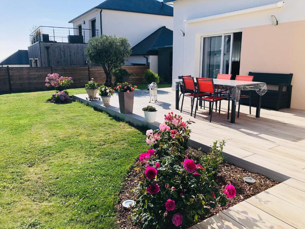 a patio with a table and chairs and flowers at Chez Yolande in Lampaul-Plouarzel