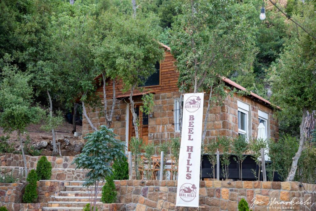 a log house with a sign in front of it at Beel Hills in Khallat al Mutayn