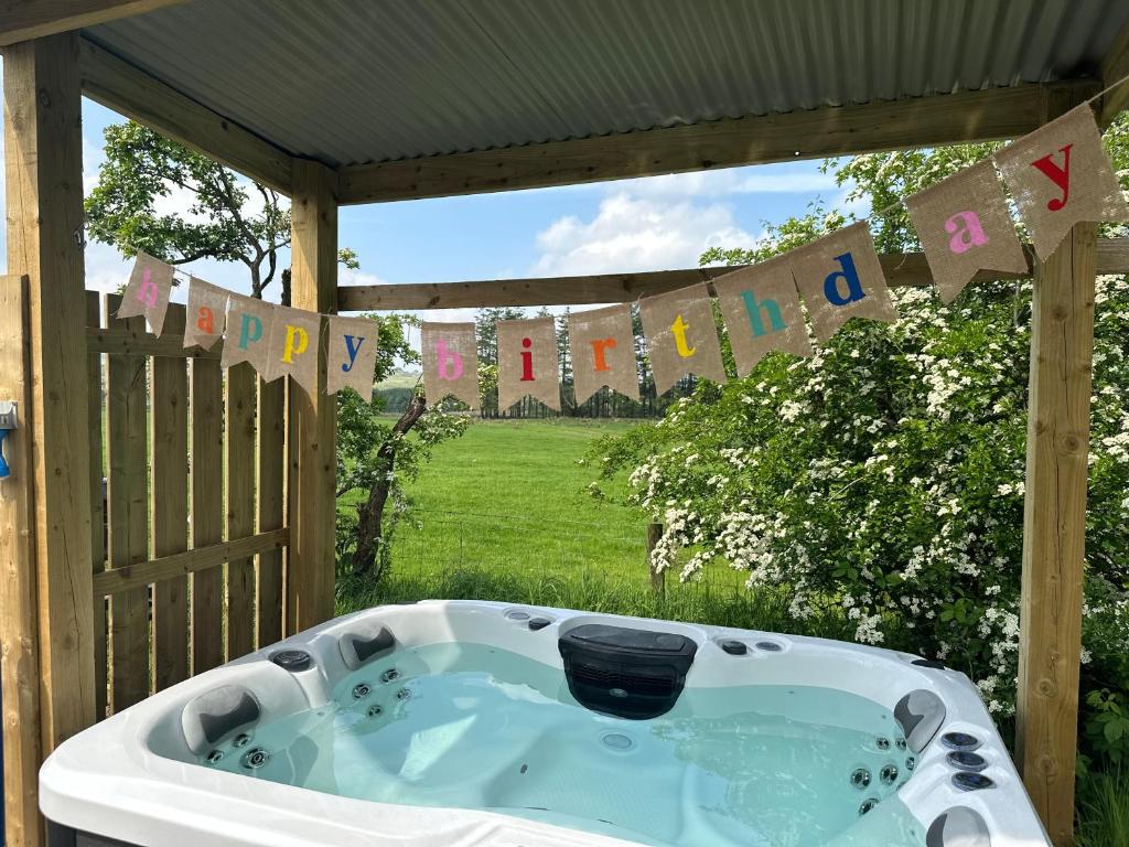 a bath tub in a yard with a birthday banner at The Truck with private hot tub -Garvagh retreats in Ballynameen