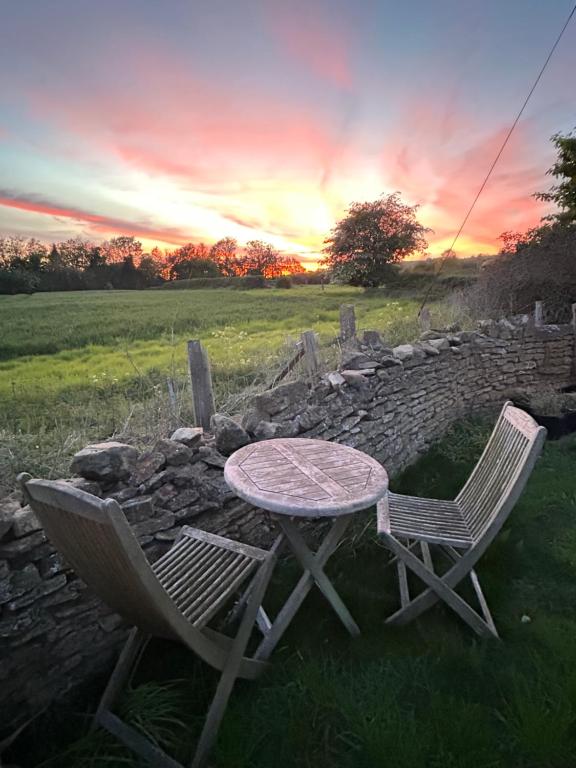 a table and chairs sitting next to a stone wall at Sunset View - Luxury accommodation in the Cotswolds in Tewkesbury