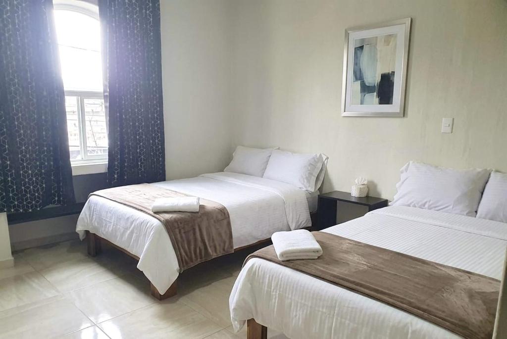 a hotel room with two beds and a window at Mi Casa Morelia in Morelia